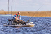 Rigged up Hobie Lynx, with plenty of fishing accessories on it being used to catch a fish